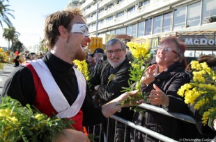 Un animateur de la BAT offre une tige de mimosa au public
